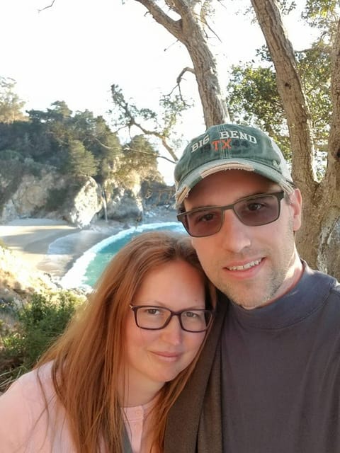 Jenn and Dan taking a selfie above a turquoise cove on the Big Sur coast