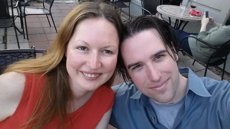 Jenn and Dan leaning together for a selfie on a restaurant patio