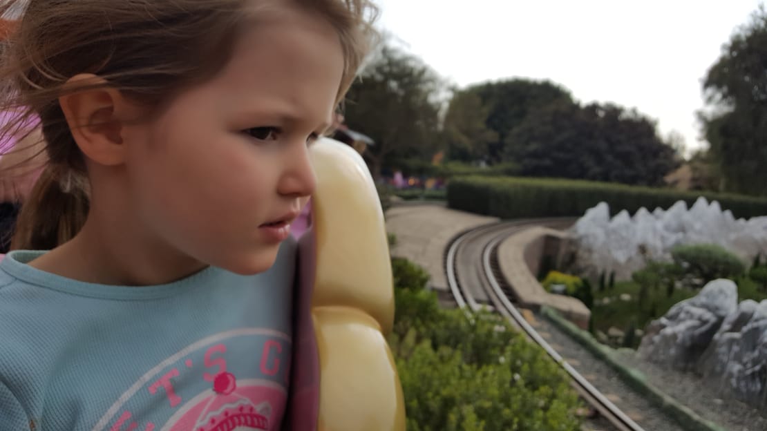Penny resting against a ride seat, watching the miniature railway track curve away through the hedges